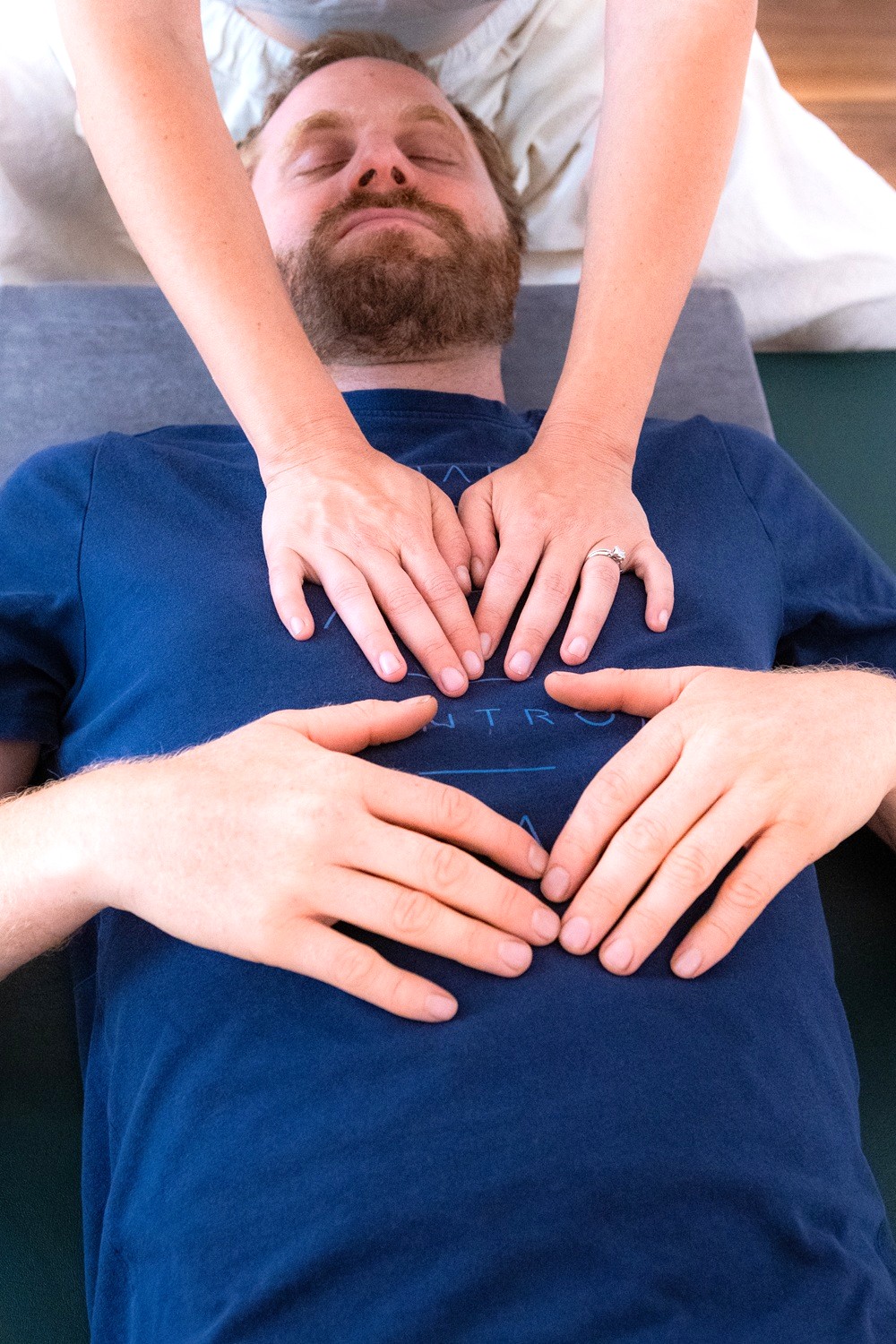 Feldenkrais: Hände begleiten die Atembewegung des Brustkorbs einer liegenden Person