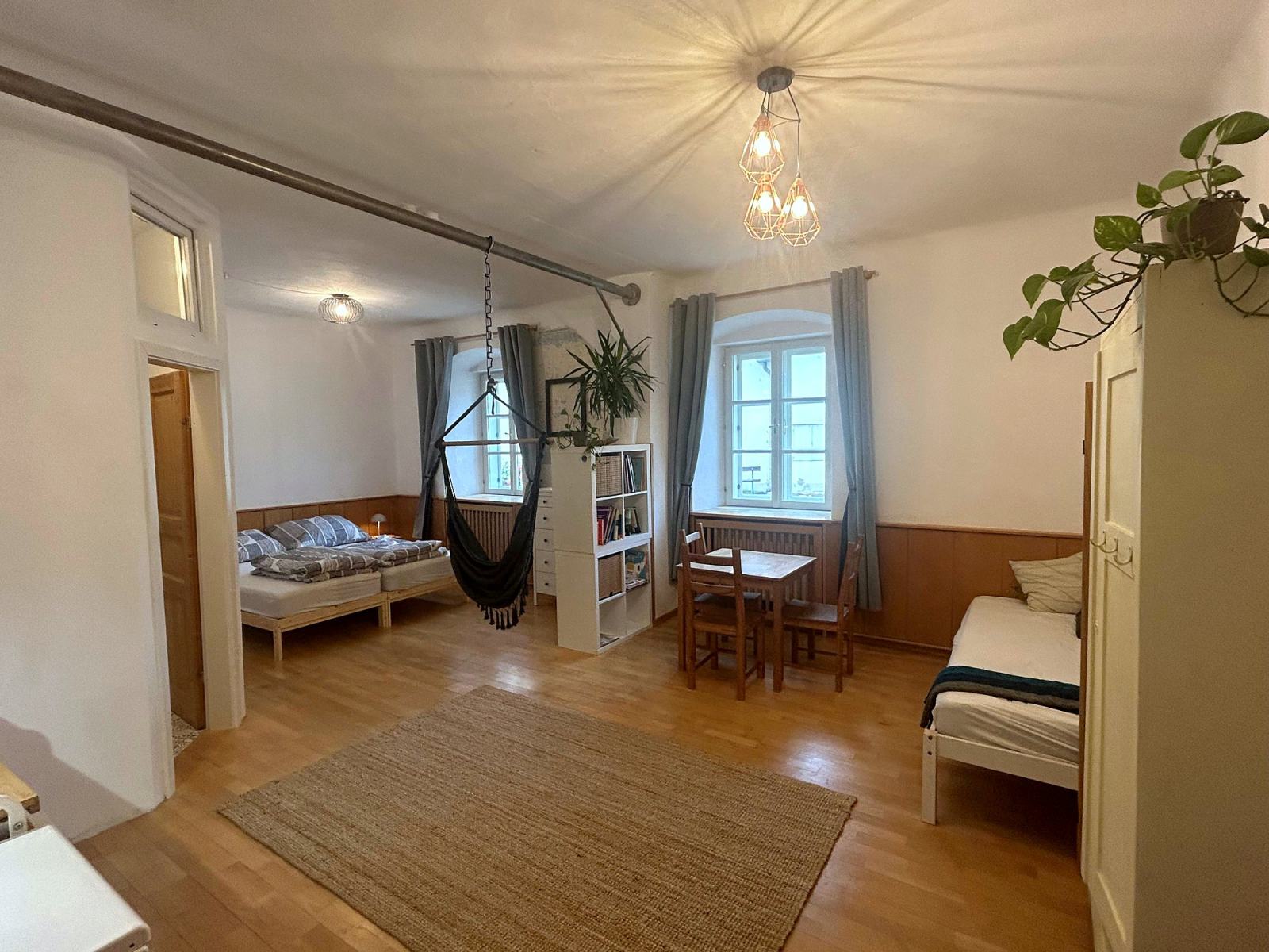 Wohnraum im Studio-Apartment mit Betten, Essplatz und Hängesessel